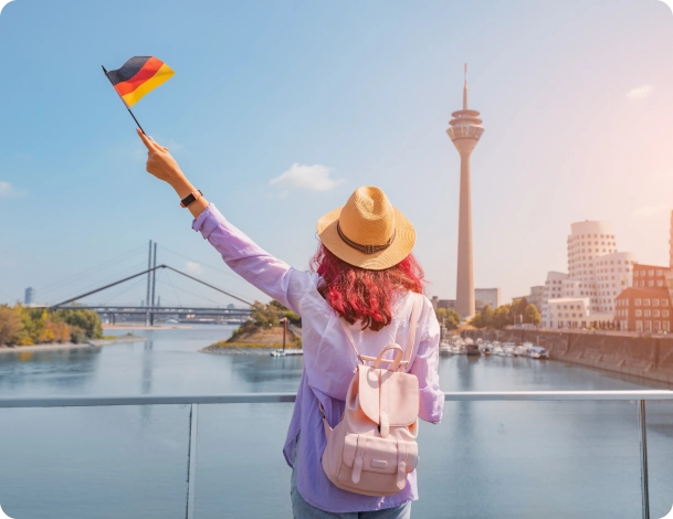 Estudante em Berlim, segurando uma bandeira da Alemanha em uma ponte em dia ensolarado