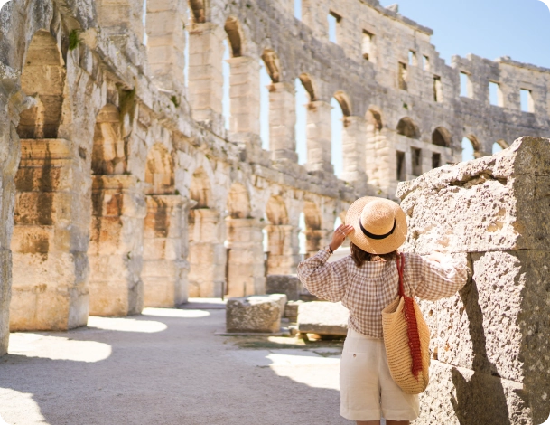Estudante em Roma com prédio histórico ao fundo em dia ensolarado